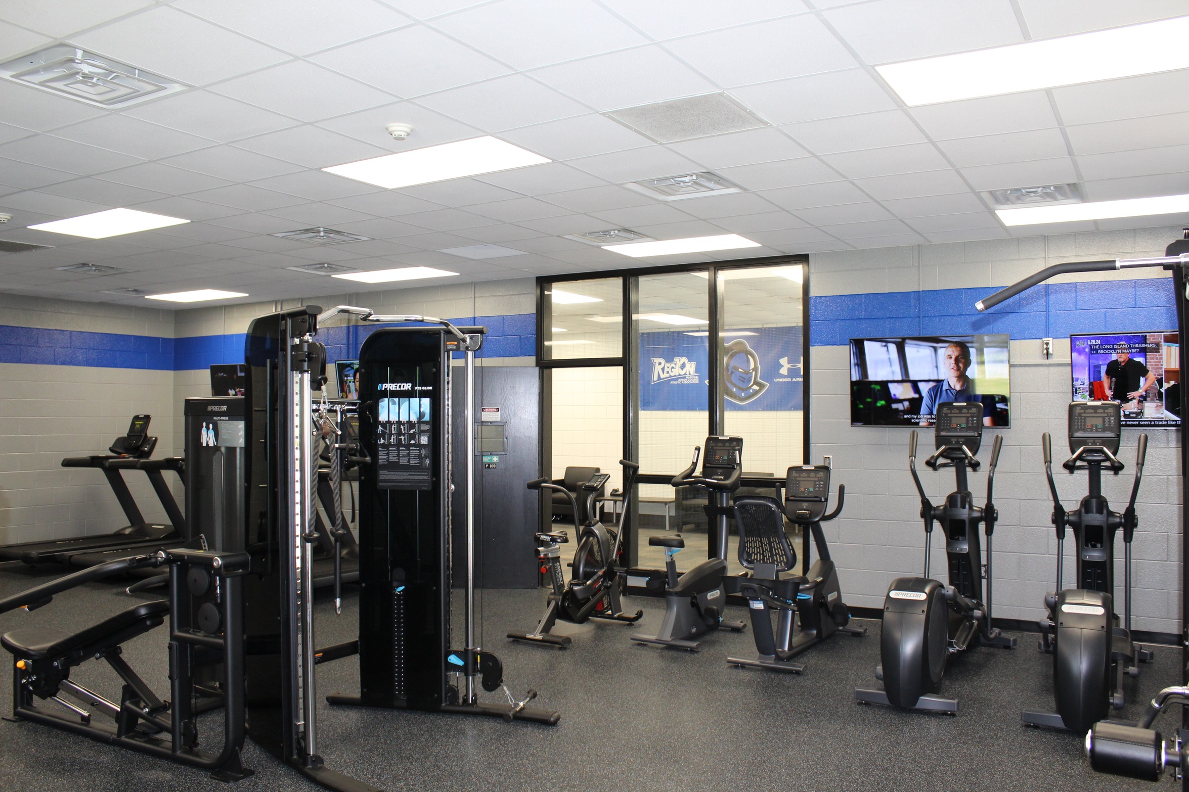 Image shows fitness room with several pieces of workout equipment i.e., cycle machines, functional training machine, treadmills.